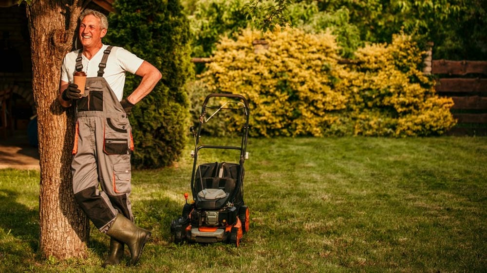 Man leaning against a tree, taking a break from mowing