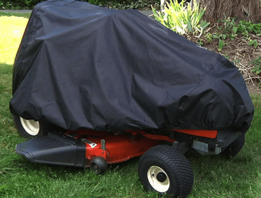Riding lawn mower covered with a black tarp, parked on a grassy lawn.