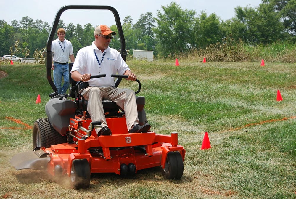 Man operating a zero-turn mower during an outdoor demonstration