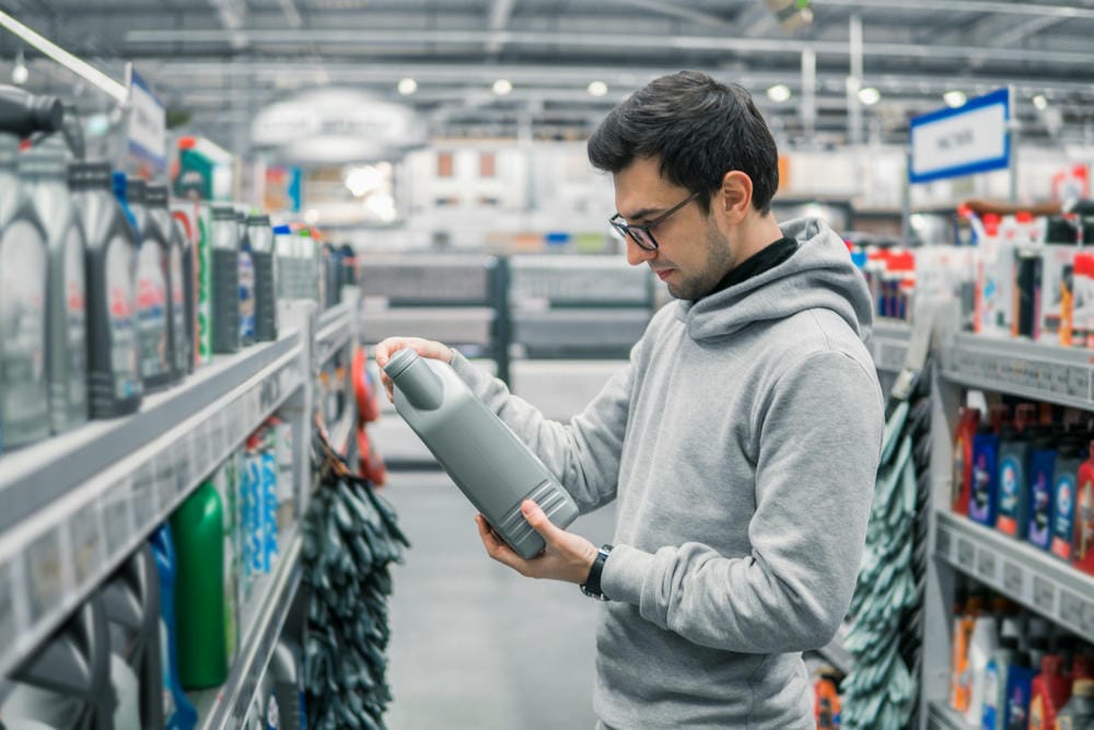 Man inspecting a motor oil bottle in a store aisle