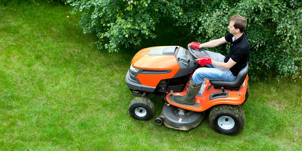 Man mowing lawn with an orange riding mower