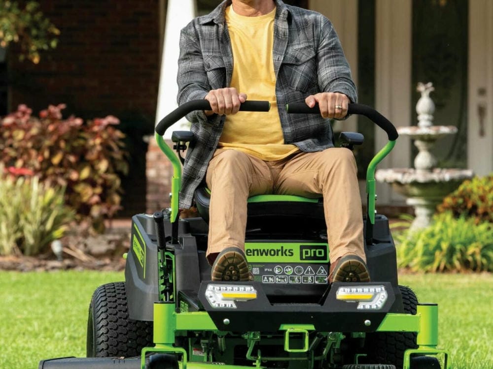 Man operating a riding lawn mower on a well-kept lawn.