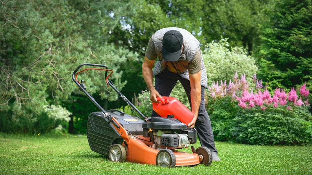 Man refueling a lawnmower in a green garden