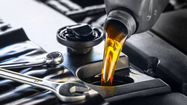 Pouring lawn mower oil into an engine with wrenches nearby