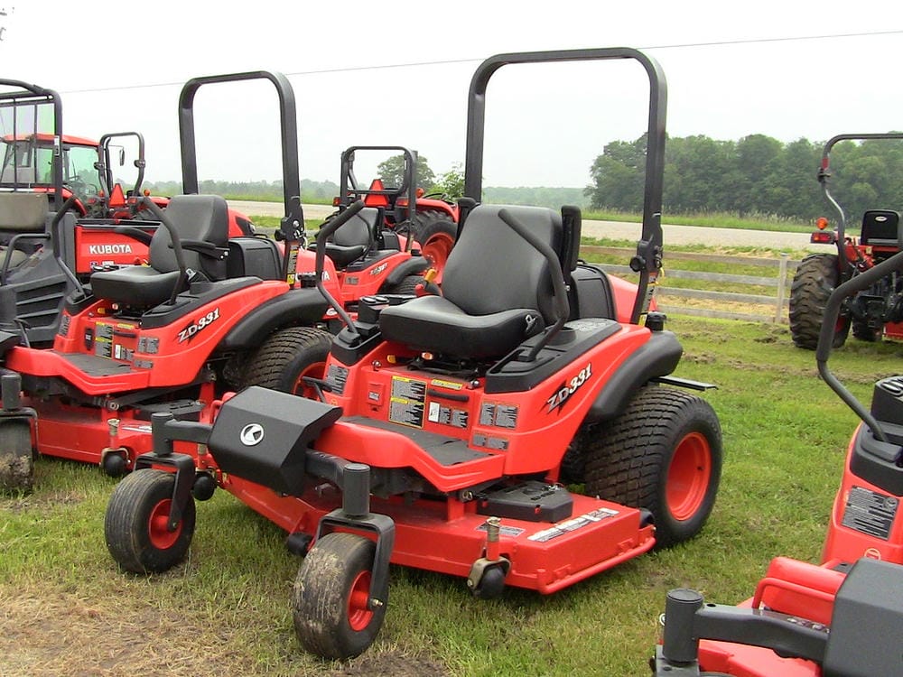 Line of red zero-turn mowers displayed outdoors.
