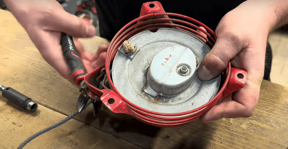 Close-up of hands fixing lawn mower’s recoil starter with a screwdriver