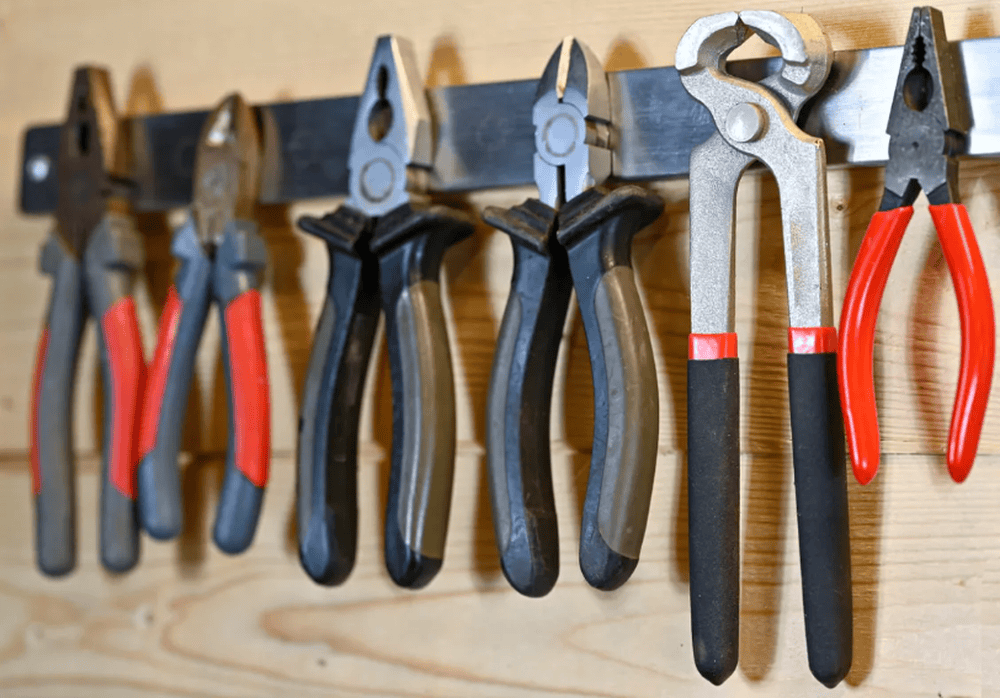 Various pliers hanging neatly on a wooden wall in a workshop